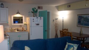A compact living space with a kitchenette, a blue sofa with patterned cushions, and a dining area with wooden furniture. - Historic Charleston Charm-1 mi beach/6 m downtown/Comfort & Safety   (Mt Pleasant)