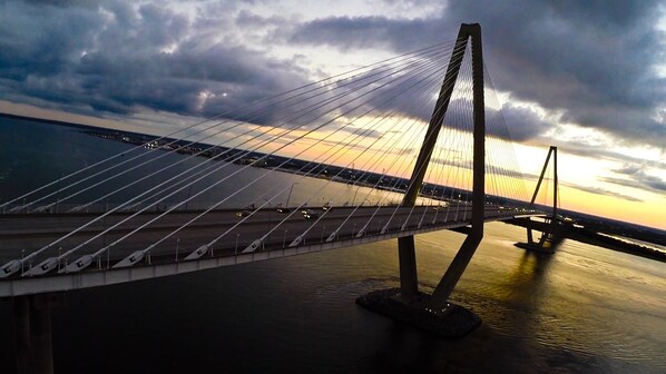 A cable-stayed bridge with a clear view of the water below and a sunset in the background.