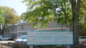 A sign for Marsh Grass Condominiums with a white background and teal lettering. - Historic Charleston Charm-1 mi beach/6 m downtown/Comfort & Safety   (Mt Pleasant)