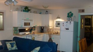 A compact living space with a kitchenette, a blue sofa with decorative pillows, and a dining area with a wooden chair. - Historic Charleston Charm-1 mi beach/6 m downtown/Comfort & Safety   (Mt Pleasant)