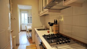 Et moderne køkken med hvide skabe, en gasblus og et vindue med udsigt til spiseområdet.