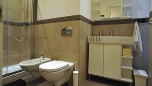 Et badeværelse med bruser, toilet, håndvask og bidet.