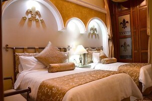 Een hotelkamer met twee bedden, een kroonluchter en decoratieve wandpanelen.