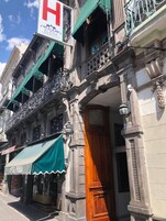 Een historisch pand met versierde balkons, een opvallend hotelschild en een traditionele houten deur.