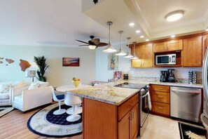A modern kitchen with wooden cabinets, stainless steel appliances, and pendant lighting.