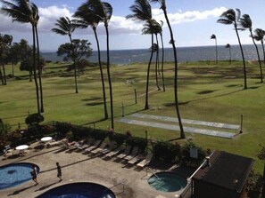 A resort with a pool area, lounge chairs, and a view of the ocean.