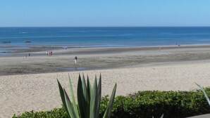 Ein Strand mit sandigem Ufer, einigen Personen und Booten im Wasser.