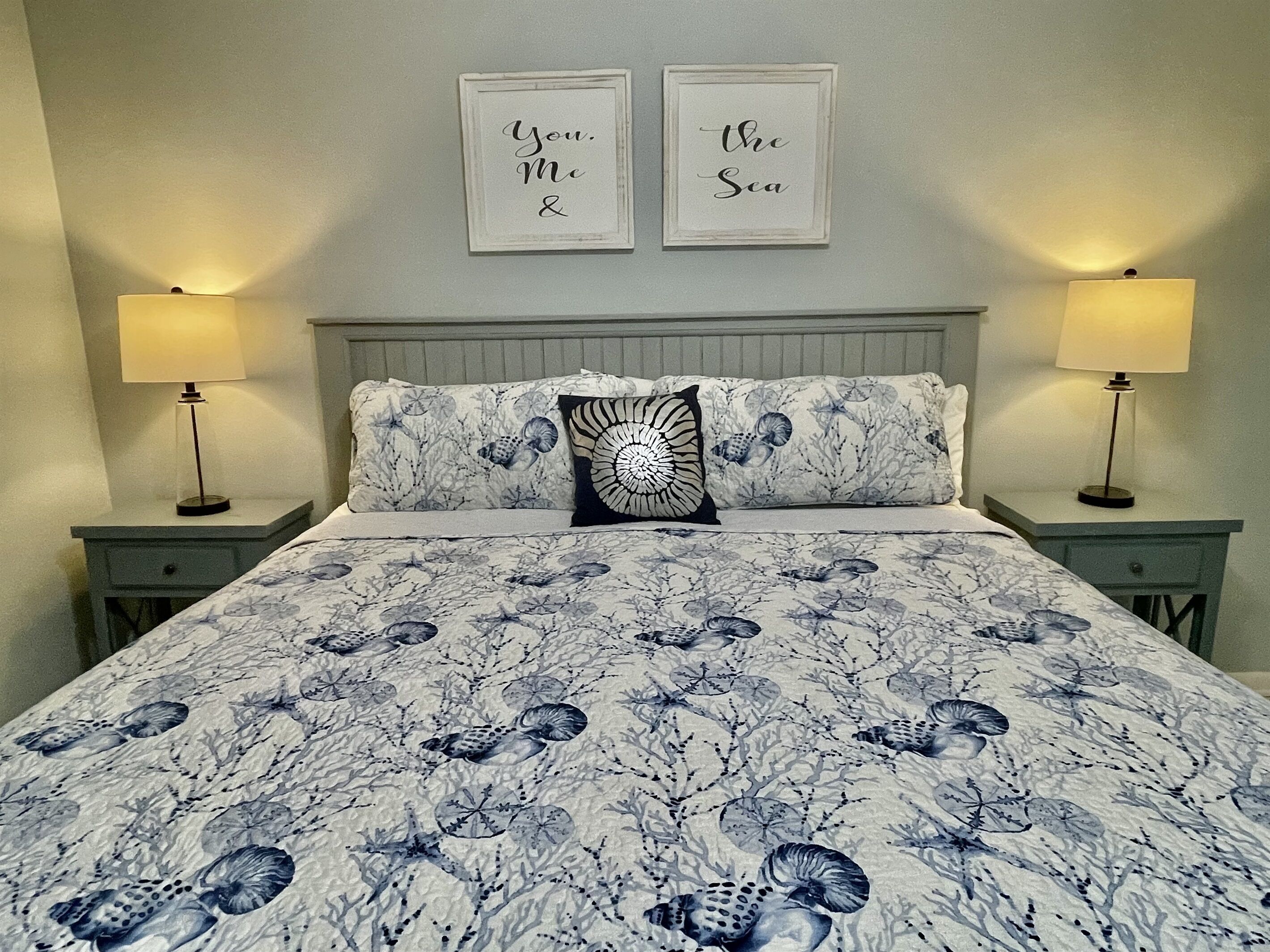 Ein Schlafzimmer mit einem Bett, zwei Nachttischlampen, einem Kopfteil und zwei an der Wand befestigten Schildern.