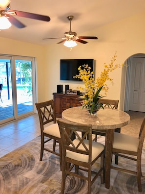 Enjoy meals in this cozy dining area with a round table and comfortable seating for four, a flat-screen TV, and a beautiful vase with fresh flowers.