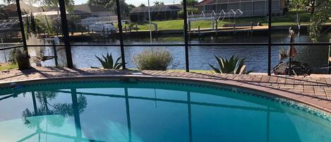 An indoor swimming pool with clear views of a residential area and a body of water outside.
