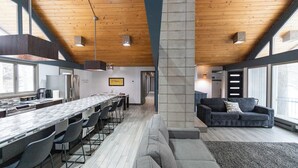 A modern kitchen with a long counter, dining chairs, and a large window. - Waterfront Home with Pontoon, Movie & Game Room-Perfect for Families & Getaways! (Park Rapids)