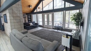 A spacious living room with a large gray sectional sofa, a dark gray couch, and a large windowed area providing natural light. - Waterfront Home with Pontoon, Movie & Game Room-Perfect for Families & Getaways! (Park Rapids)