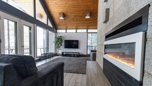 A modern living room with a fireplace, a large TV, and a seating area. - Waterfront Home with Pontoon, Movie & Game Room-Perfect for Families & Getaways! (Park Rapids)