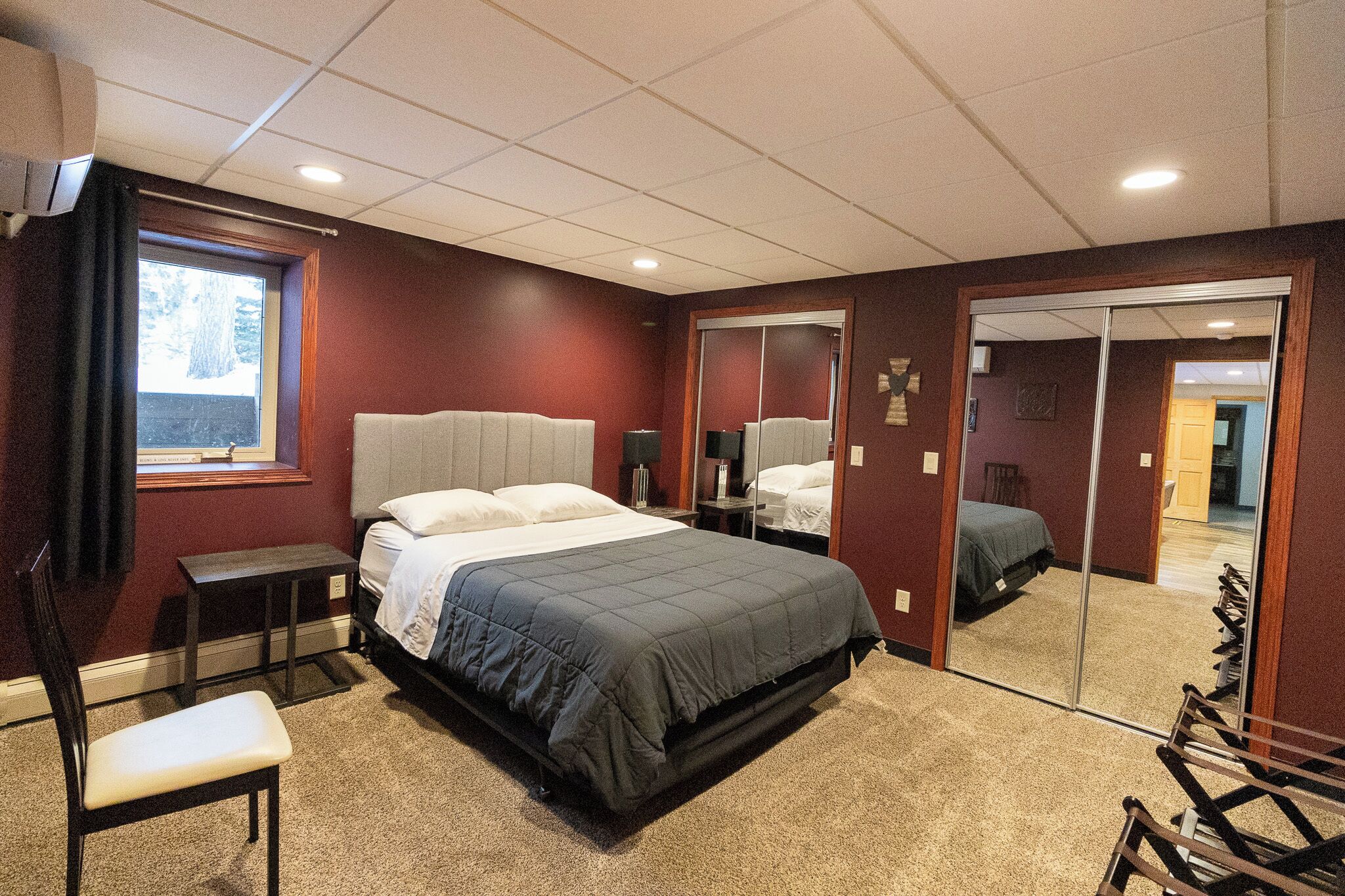 Une chambre d’hôtel avec un grand lit, un bureau, une chaise et un miroir.