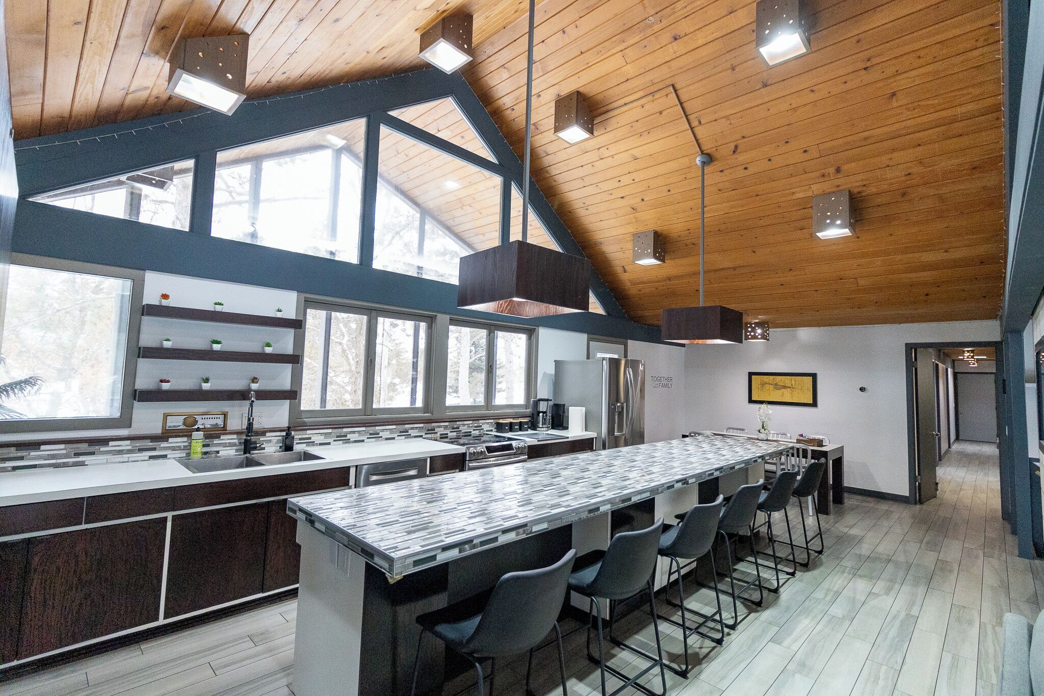 Una cocina moderna con una isla grande, taburetes de bar y vistas al exterior a través de amplios ventanales.
