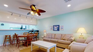 A living room with a dining area, a ceiling fan, a sofa, a coffee table, and a lamp. - Large Garage for Boat, Shared Pool , Pet Friendly, Golf Cart Access (Port Aransas)