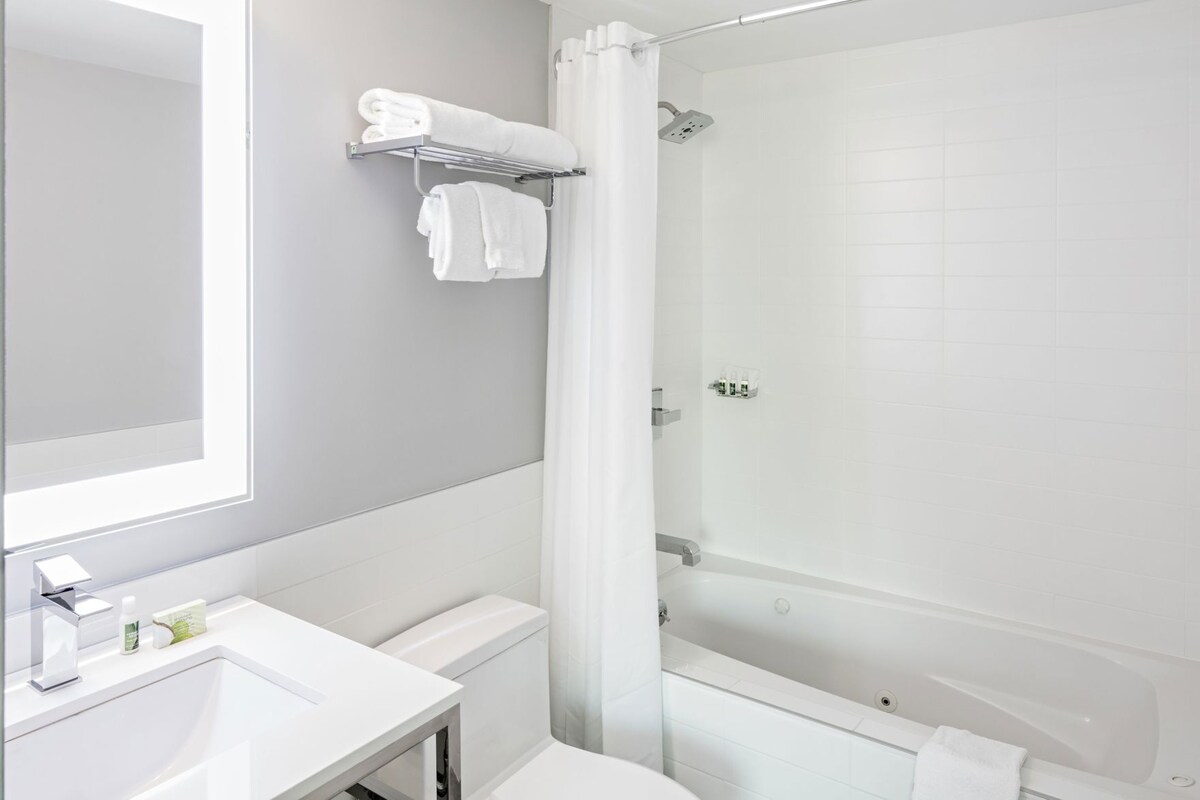 Badkamer | Een bad/douchecombinatie, designer toiletartikelen, een haardroger