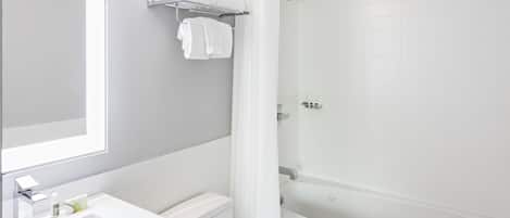 Une salle de bain moderne avec un lavabo blanc, un miroir et une baignoire.