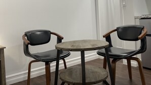 Un comedor con una mesa redonda y cuatro sillas, un cuadro de una playa y una puerta blanca.