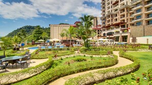 A resort with a pool area, outdoor seating, and a landscaped garden. - The Palms 101 (Jacó)