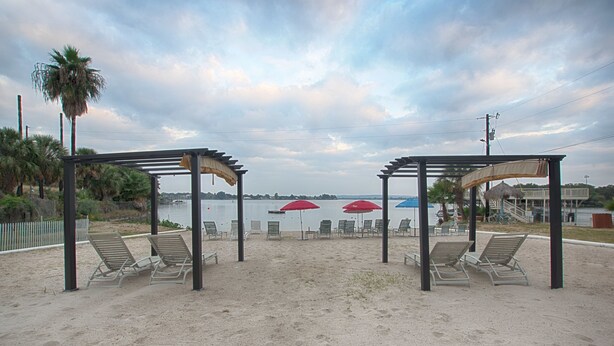 A beach with two shaded areas, each with a pergola and lounge chairs.