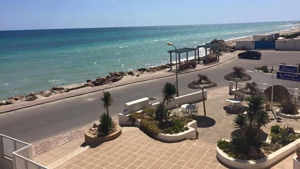 Un hôtel situé sur la côte, doté d’une promenade dallée, d’un espace extérieur aménagé pour s’asseoir et offrant une vue sur l’océan.