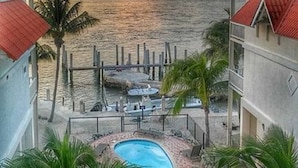 Un complexe hôtelier doté d’une piscine, de palmiers et offrant une vue sur l’océan au coucher du soleil.