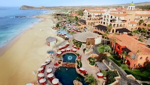 Ein Resort mit mehreren Schwimmbecken, einem Strand und einer Bergkulisse.