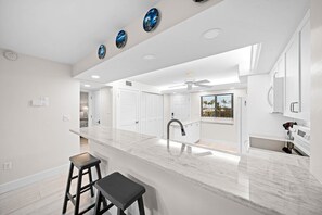 A modern kitchen with a marble countertop, a built-in sink, and a ceiling fan.