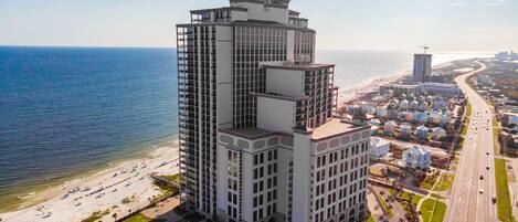 A high-rise hotel with multiple floors, a beach view, and a parking area.