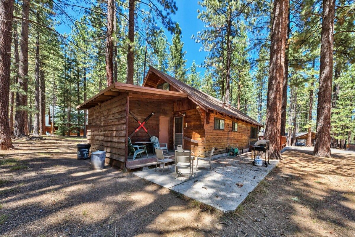 A cabin with a porch, outdoor seating, and a grill area.