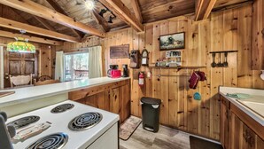 Una cucina rustica con pareti in legno, un fornello, un lavello e una finestra che si affaccia su un patio.