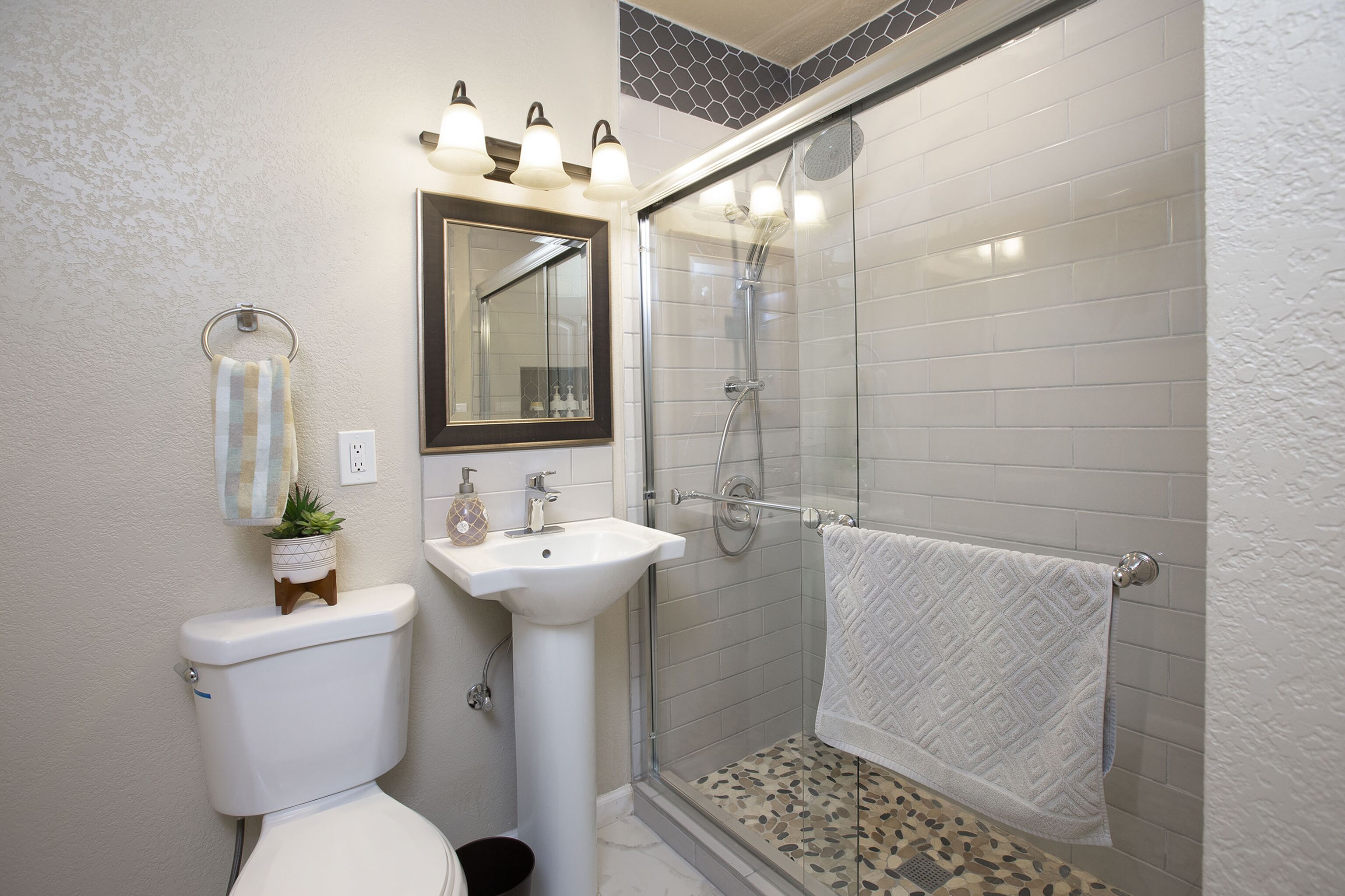 A bathroom with a toilet, sink, and glass-enclosed shower.