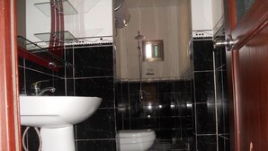 A bathroom with a white sink, a toilet, and black tiled walls. - Residence La Suite (St. Louis)