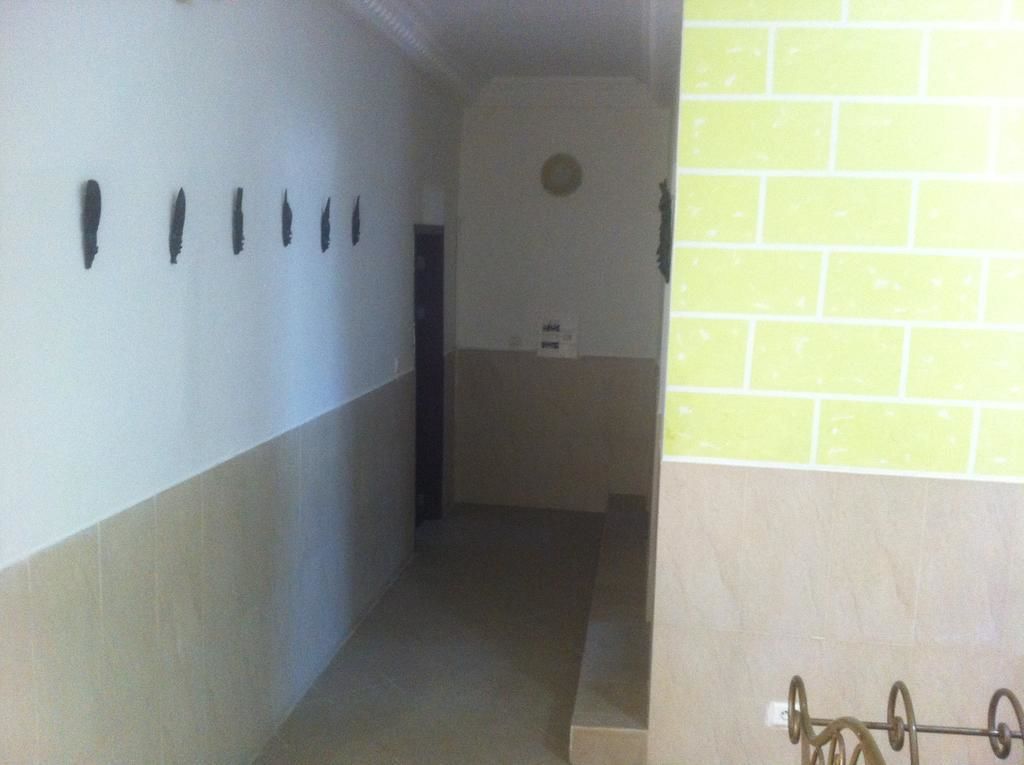 Un pasillo estrecho con una pared de azulejos a la derecha y una puerta al final.