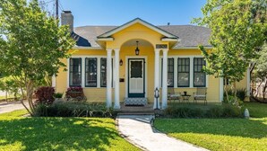 A yellow house with a number 609 sign, a front porch with a bench, and a small garden. - Garrett House | Hill Country retreat Kerrville - pool - hot tub - outdoor shower (Kerrville)