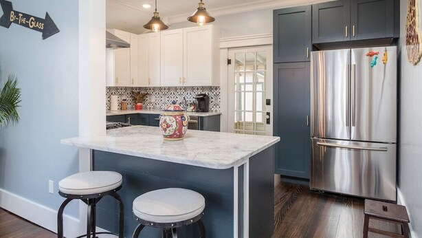 A kitchen with a marble island, two bar stools, a stainless steel refrigerator, and pendant lighting. - Garrett House | Hill Country retreat Kerrville - pool - hot tub - outdoor shower (Kerrville)