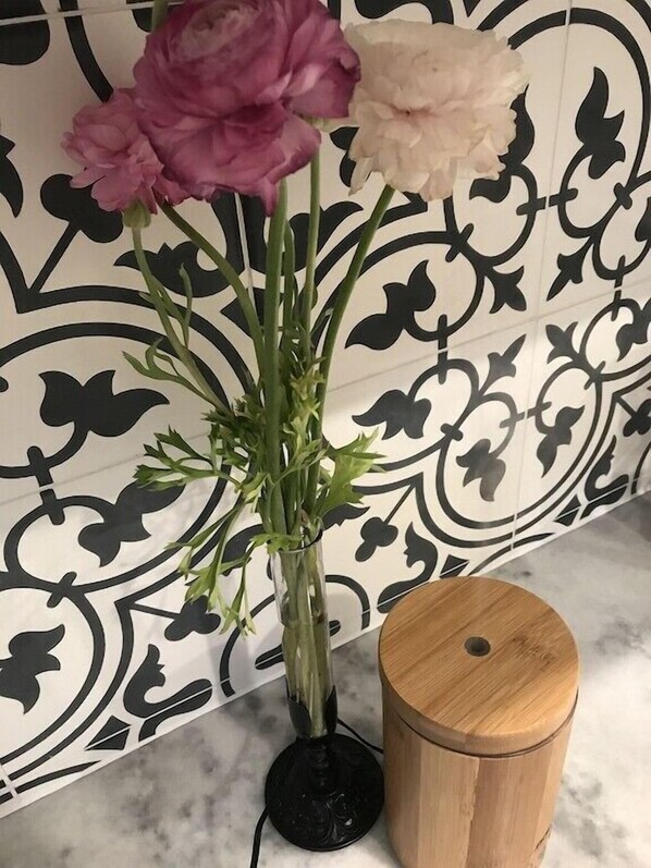 Un vase avec des fleurs et un tabouret en bois.