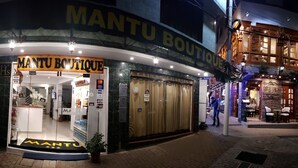 Entrada de un hotel boutique con el cartel 'MANTU BOUTIQUE', un mostrador de recepción y una puerta de acceso visible.