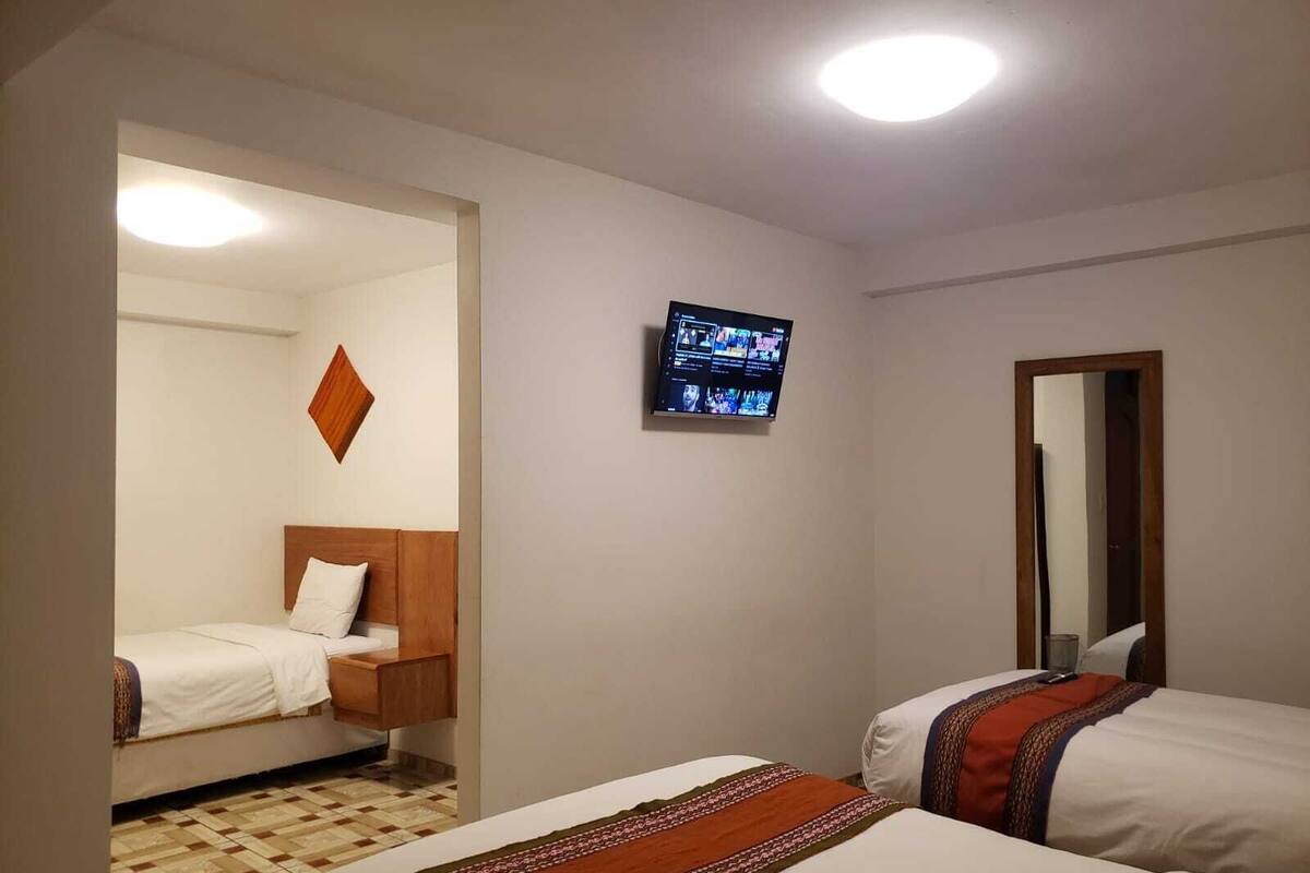 A hotel room with two beds, a television mounted on the wall, and a mirror on the opposite wall.