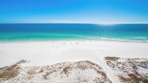 A wide sandy beach with a clear blue sea and a distant shoreline. - The Oasis 1401 | Gulf-Front Corner Luxury Retreat (Orange Beach)