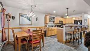 A modern kitchen with wooden cabinets, a central island, and bar stools.