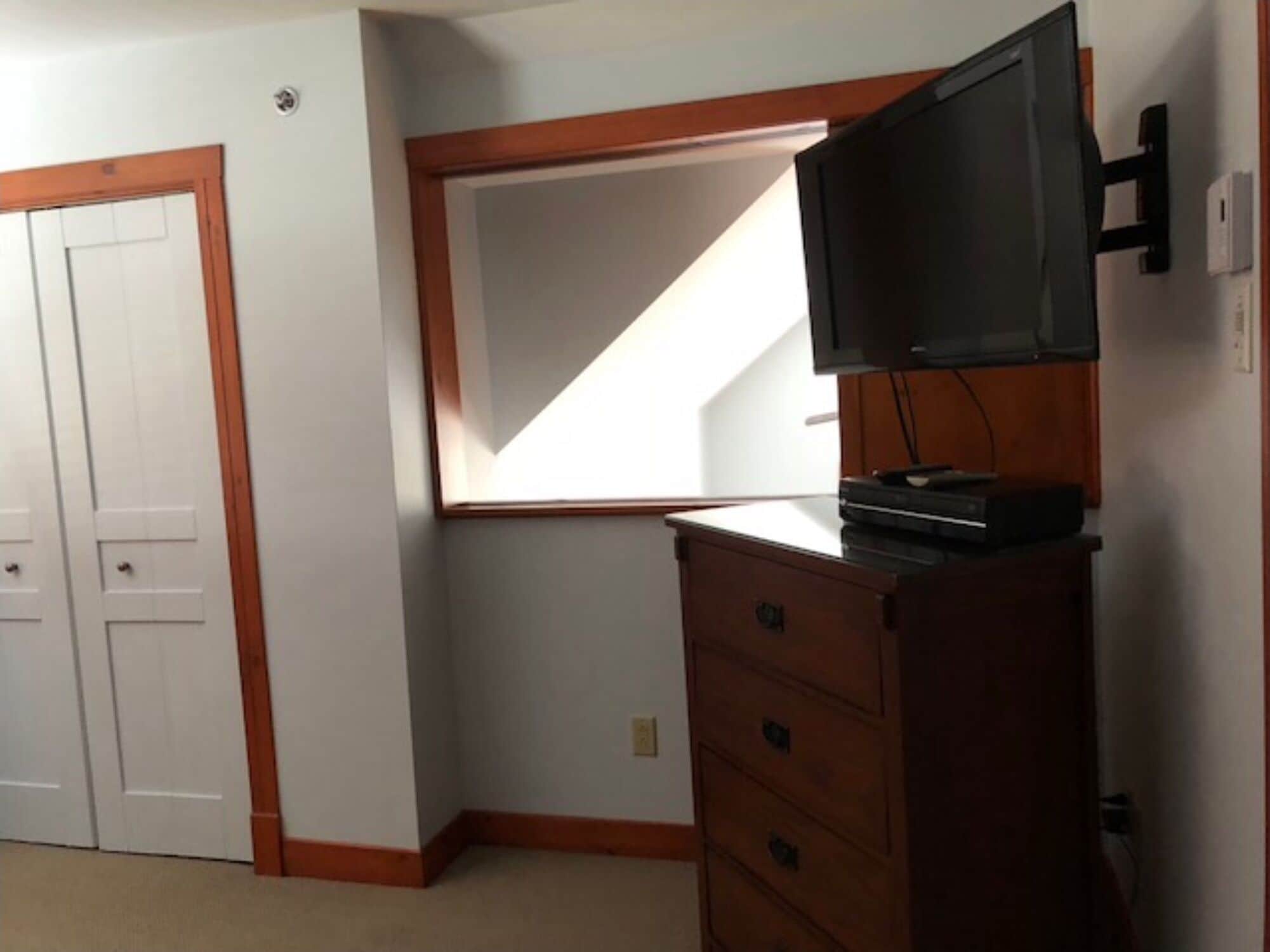 Una habitación con un aparador de madera, un televisor encima y un espejo grande en la pared.