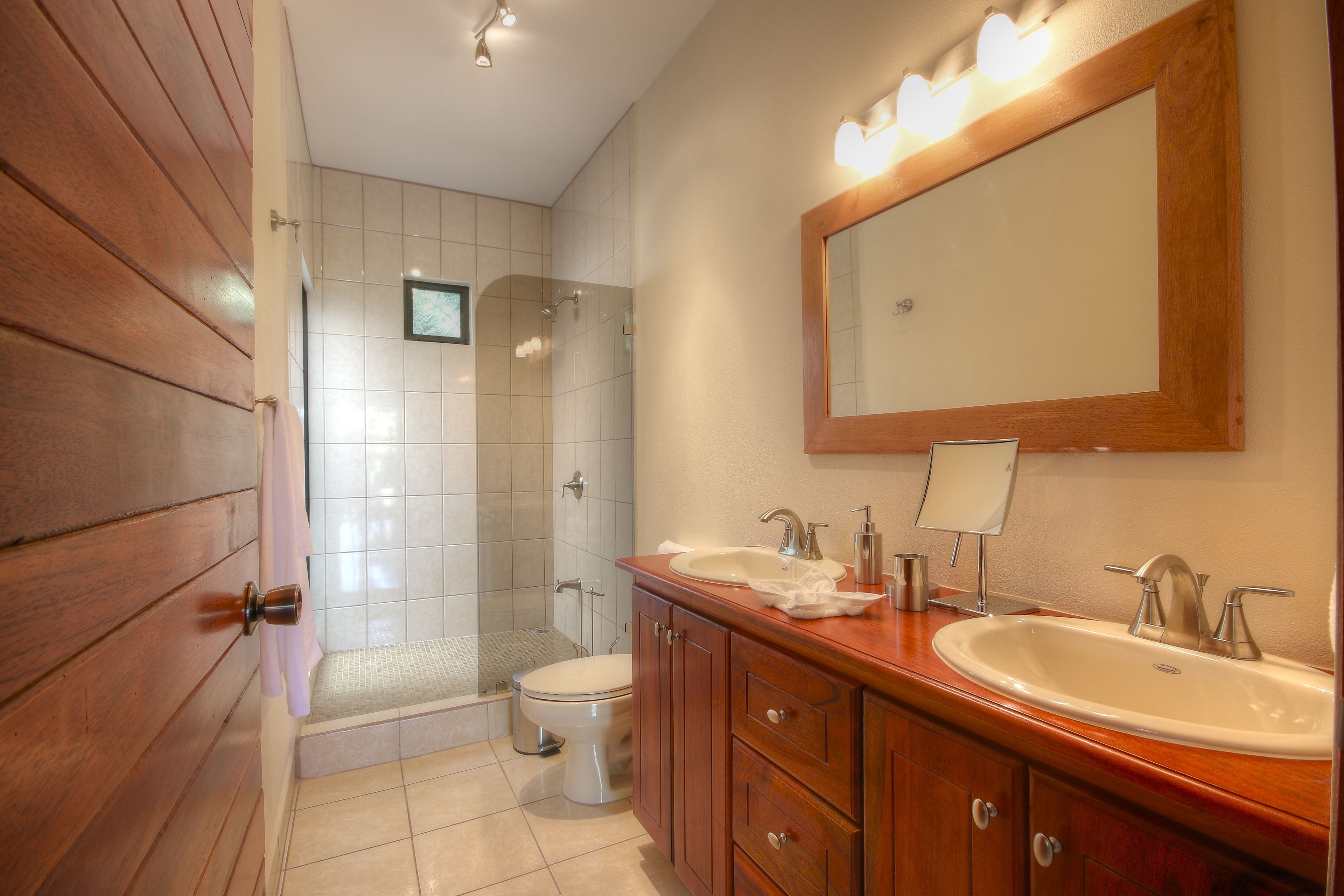 A bathroom with wooden paneling, a white toilet, a shower, and a vanity with a mirror.