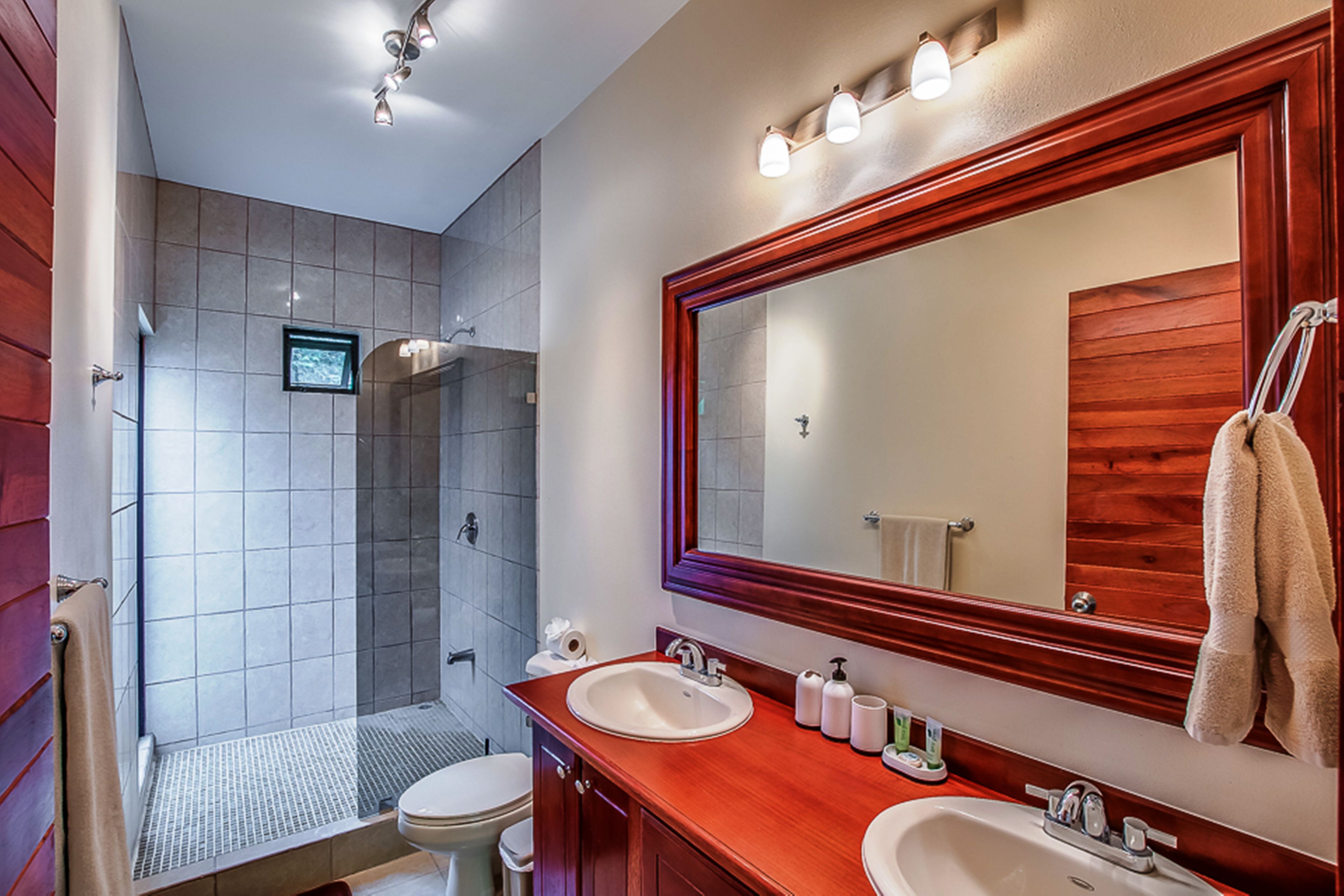 Une salle de bain moderne avec un grand miroir, deux lavabos et un espace douche.