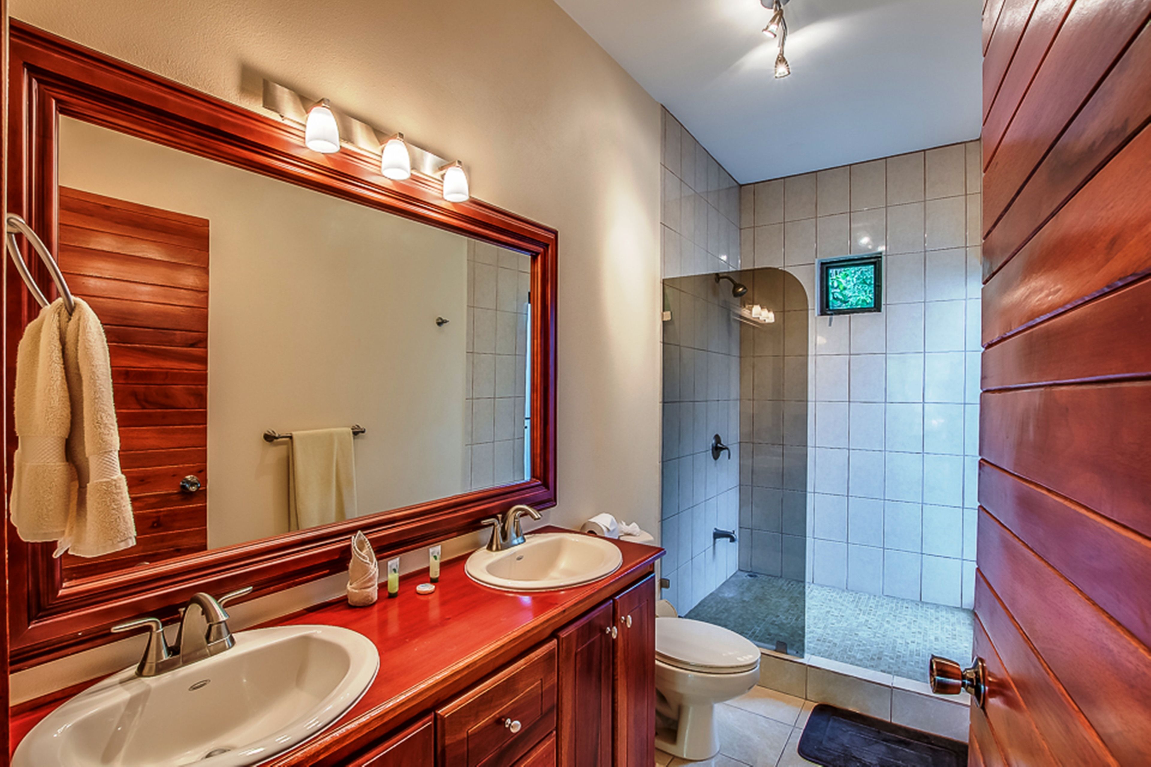 A bathroom with two sinks, a large mirror, and a shower area.