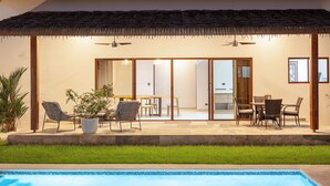 A poolside area with a thatched roof, sliding glass doors, and outdoor furniture. - Hidden Palms Nosara (Nosara)