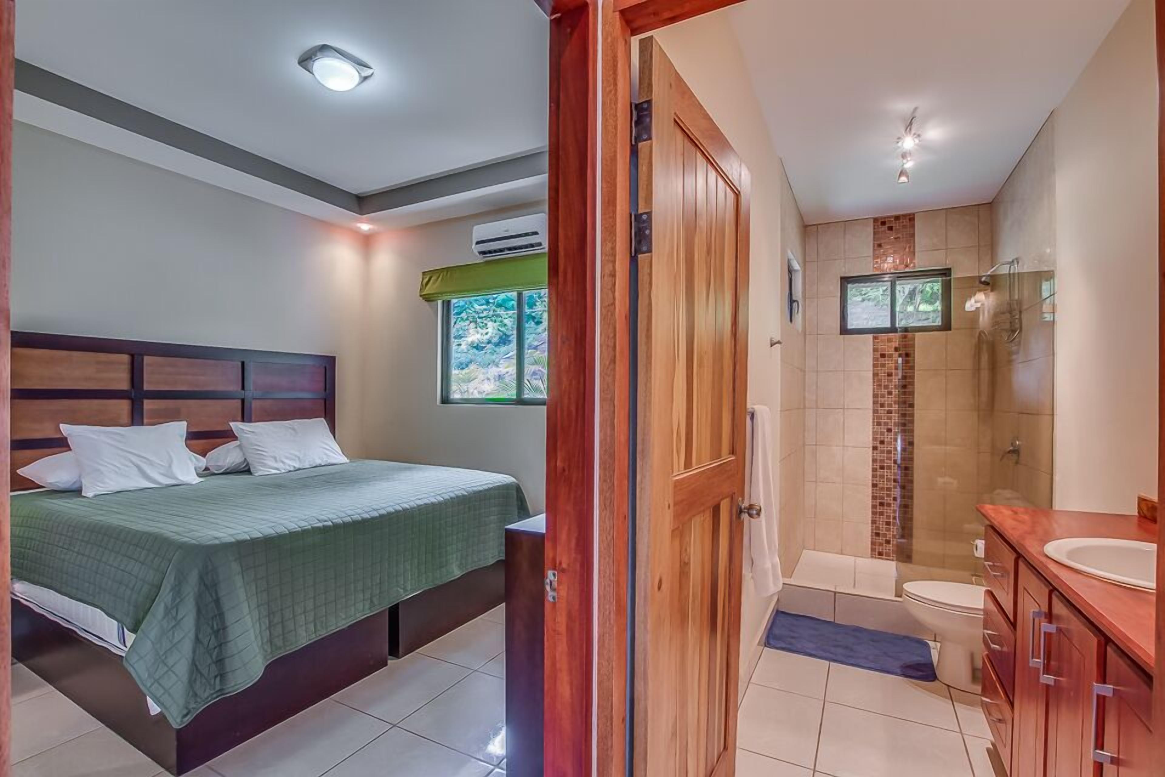 Un dormitorio con cama, un baño con ducha y vistas al exterior.