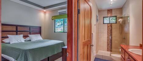 Un dormitorio con cama, un baño con ducha y vistas al exterior.