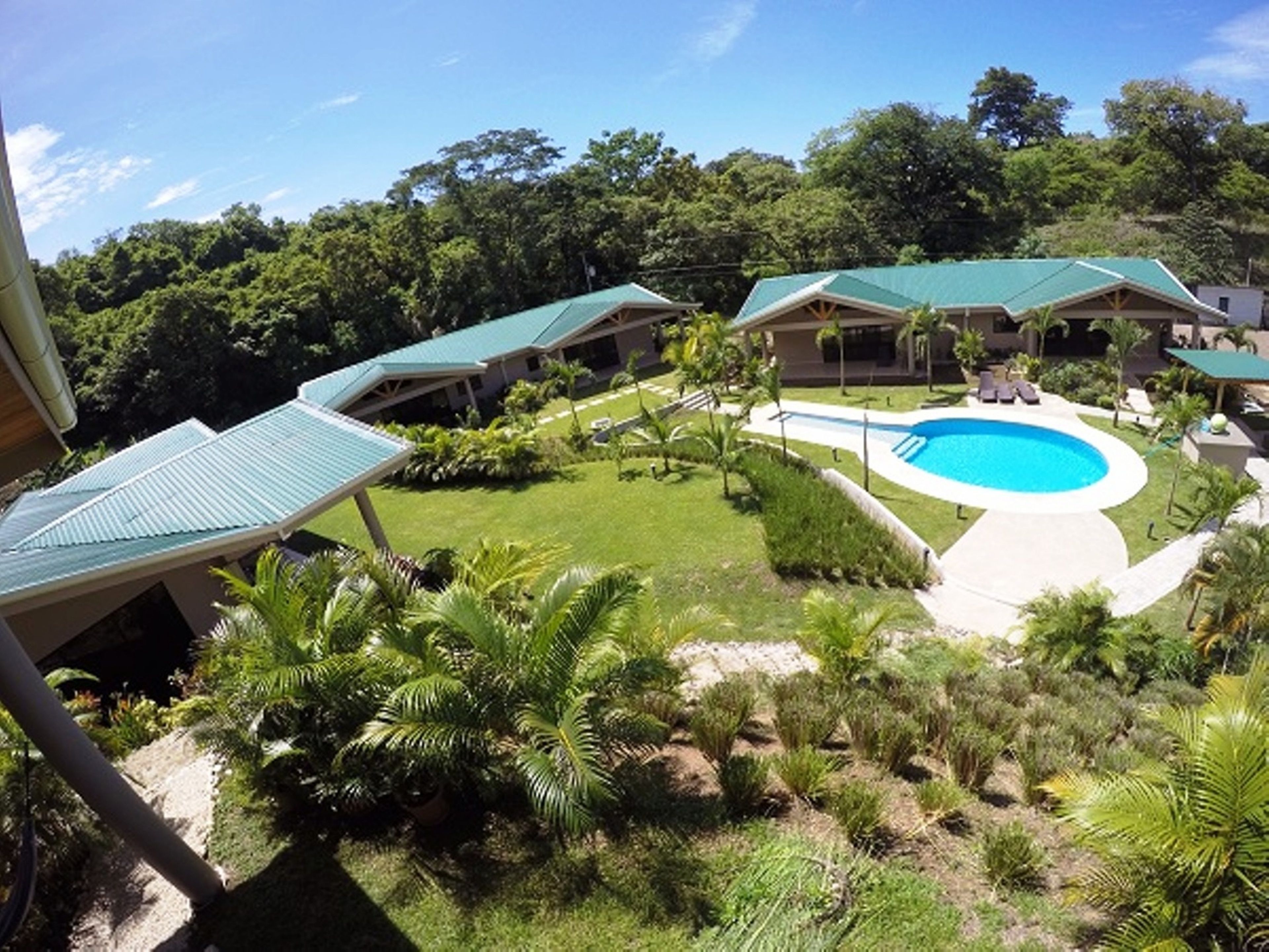 A resort with a swimming pool, multiple buildings with green roofs, and lush greenery.